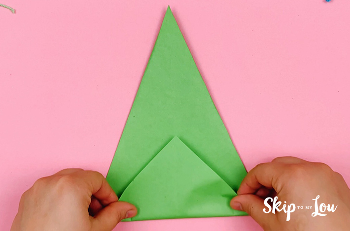 After the paper has been flipped over, two hands folding the bottom upwards.