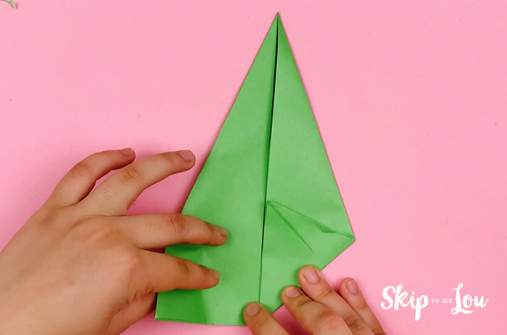 Two hands folding the bottom right corner updwards towards the center line.
