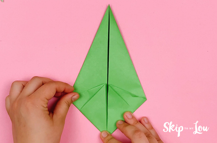 Two hands folding the bottom left corner updwards towards the center line.