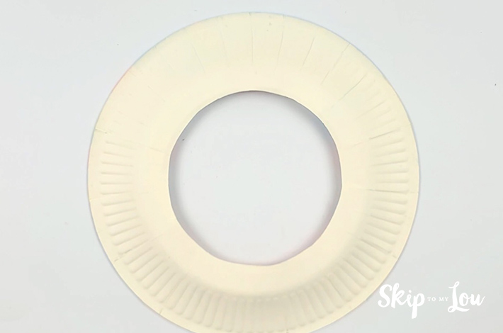 A paper plate with a circle cut out in the middle.