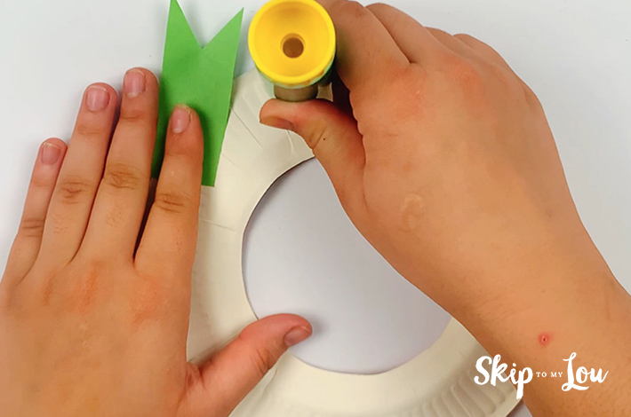 Two hand applying glue to the plate.