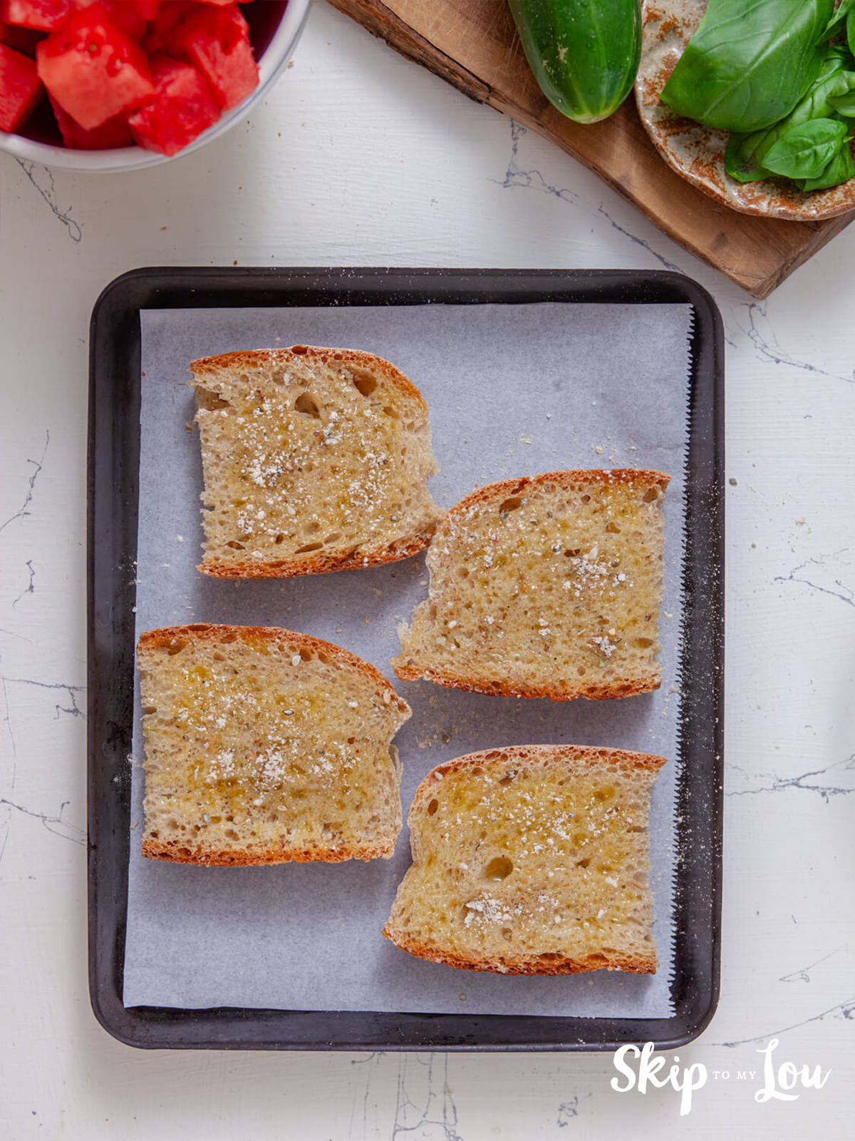 Italian bread slices on a pan brushed with olive oil and seasoned wiht the spice mix.