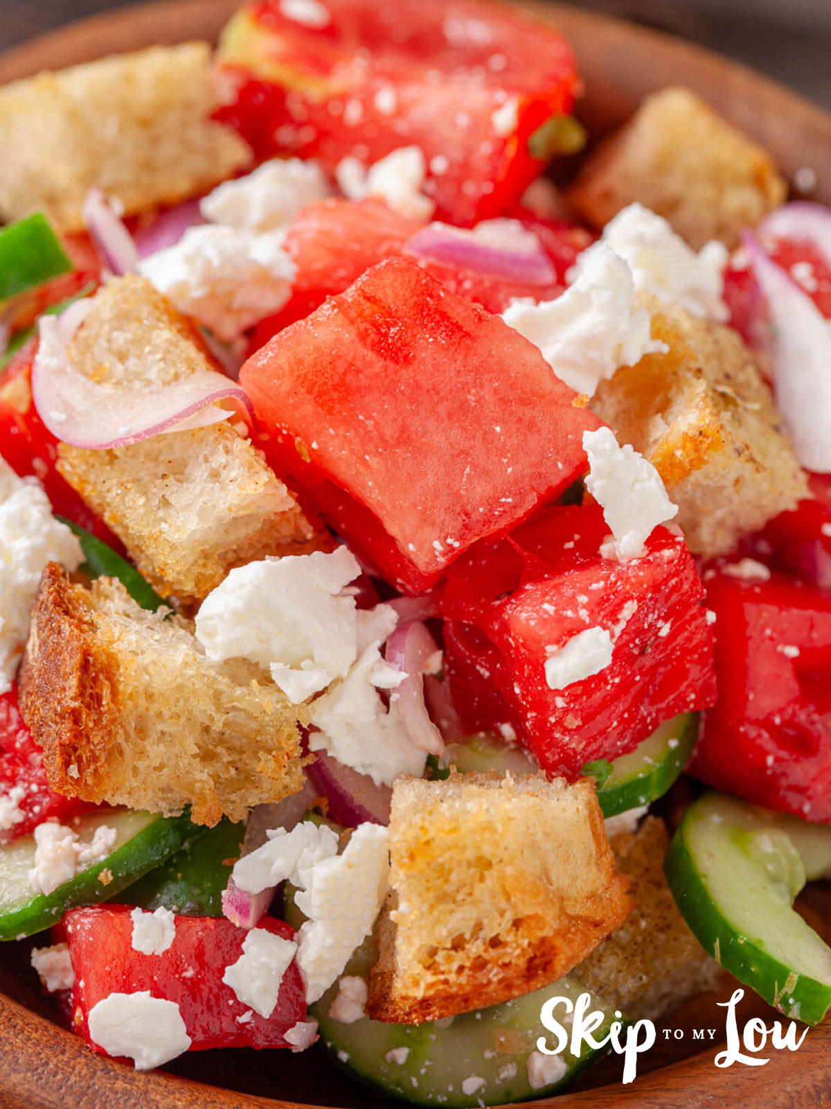 A watermelon panzanella salad  packed with added ingredients including feta, bread, red onion and herbs.
