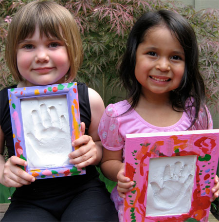 Two children holding up their hand prints in plaster of paris.