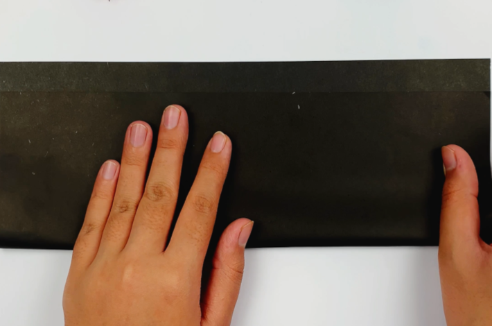 Two hands folding the paper upwards, but leaving an inch free at the top.