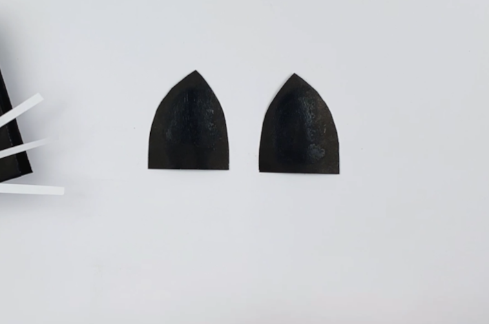 Black paper cut into two cat ear shapes.