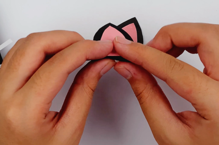 Two hands folding a small section at the bottom of the ears over.