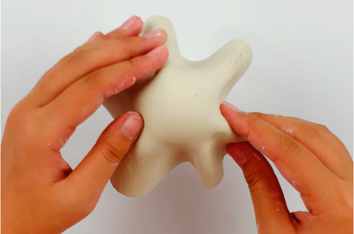 Two hands forming the modeling clay into a ghost shape. 