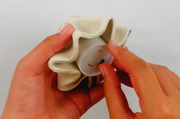 Two hands placing the battery-powered light into the underside of the ghost. 