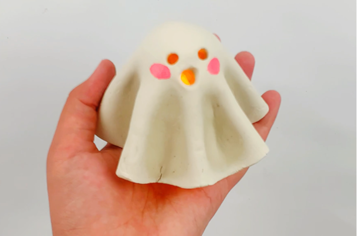 A hand holding the finished ghost tealight. 