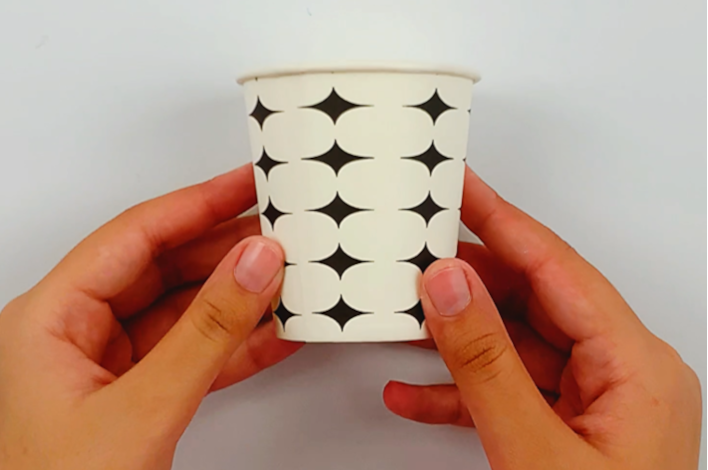 Two hands holding a paper cup. 