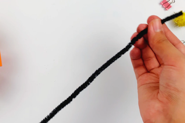 A hand holding a craft pipe cleaner.