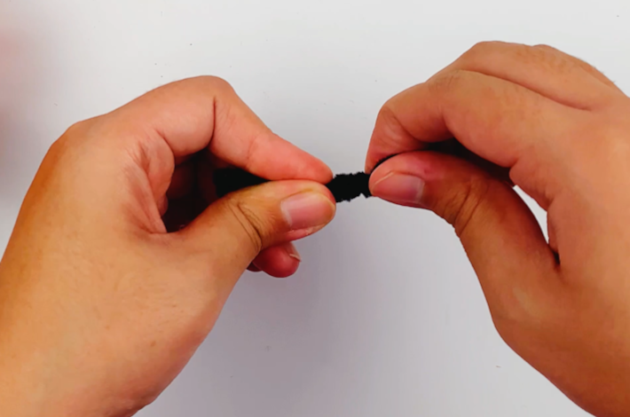 Two hands twisting the craft pipe cleaner.