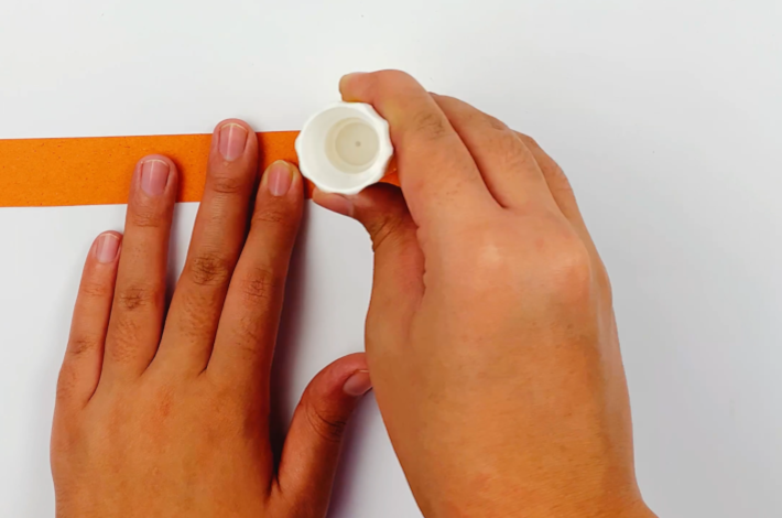 Two hands applying glue to the end of one strip.