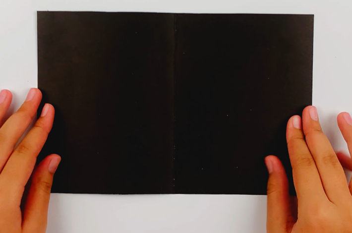 Two hands holding the A4 poster card. 