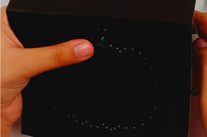 Two hands starting to thread the pumpkin stalk with the green string.
