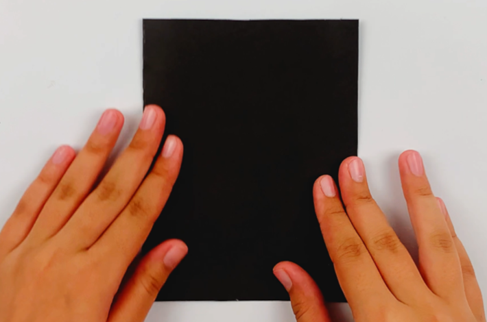 Two hands folding the A4 poster card in half from left to right. 