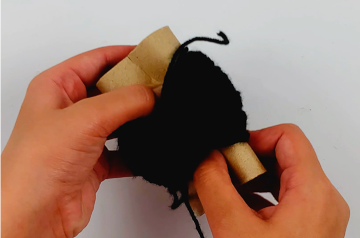 Two hands crunching the cardboard roll inwards.
