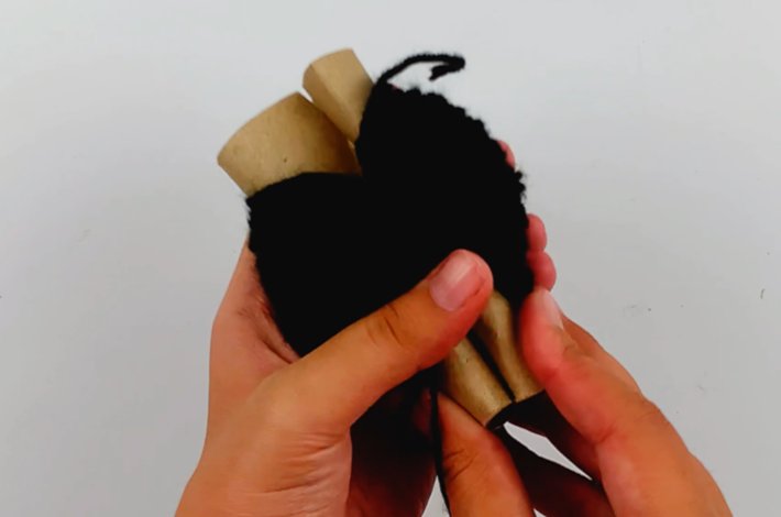 Two hands pulling the wool off the cardboard roll.
