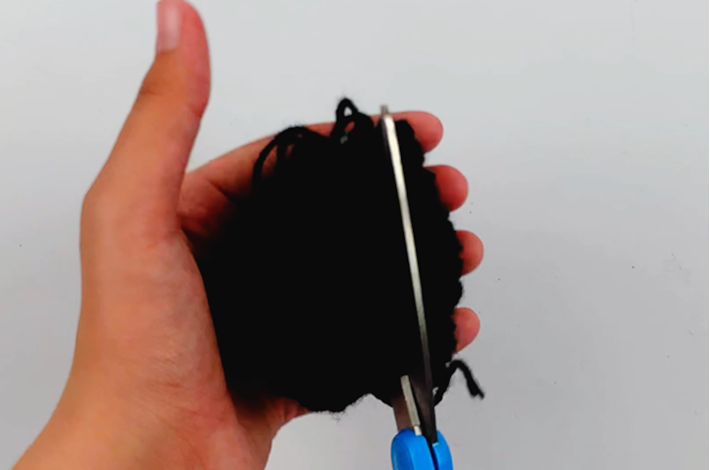 Two hands cutting the wool on the sides of the secure section.