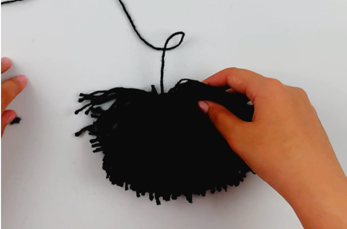 Two hands holding the ball of wool after the sides have been cut.