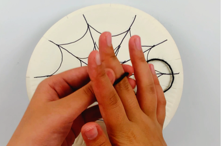 Two hands making a loop at the end of the string and attaching it to a finger.