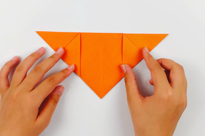 Two hands folding the top flap on the left over.