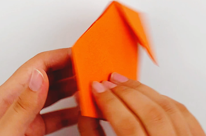 Two hands flipping the paper over 180 degrees.