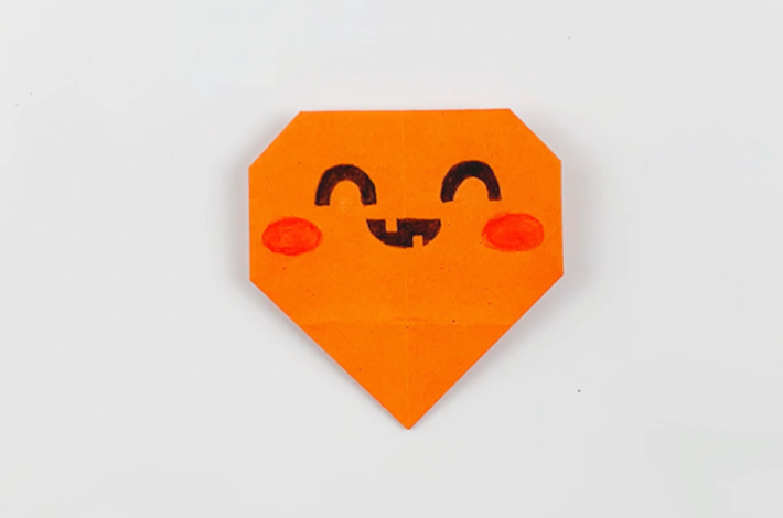 The origami gift bag after eyes, a mouth and pink cheeks have been added.
