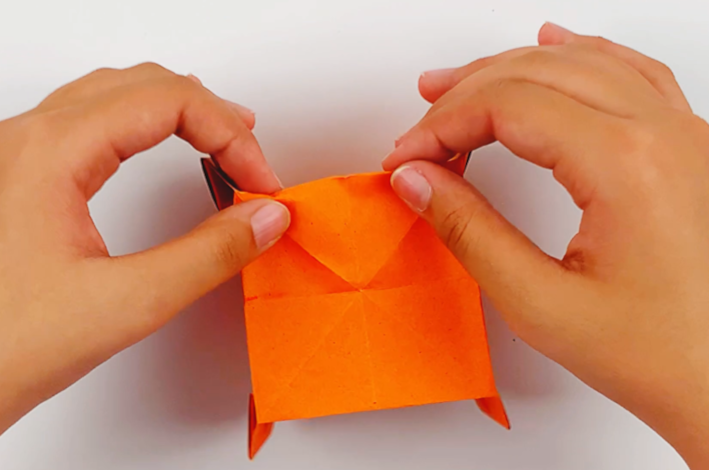 Two hands crimping the bottome edge of the gift bag.