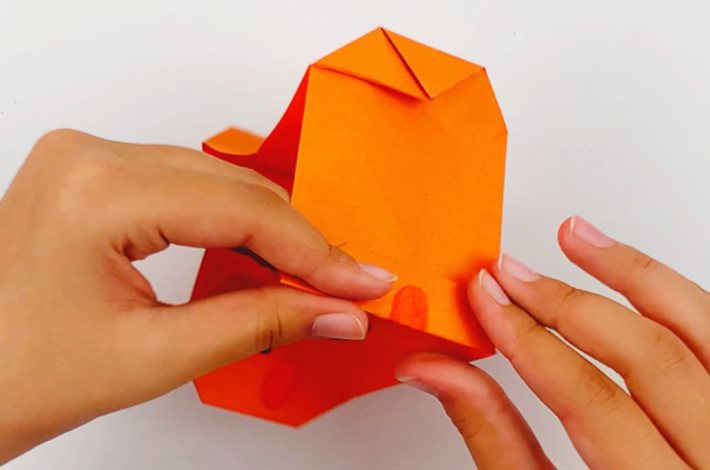 Two hands crimping the corners of the gift bag to provide stability. 