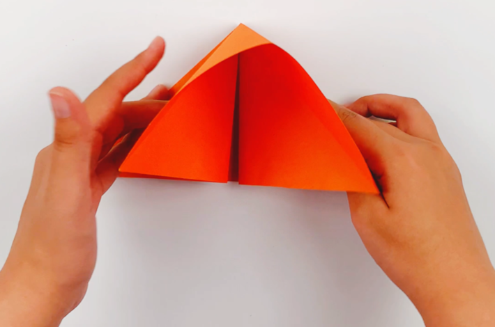 Two hands tucking the middle section folds inwards. 