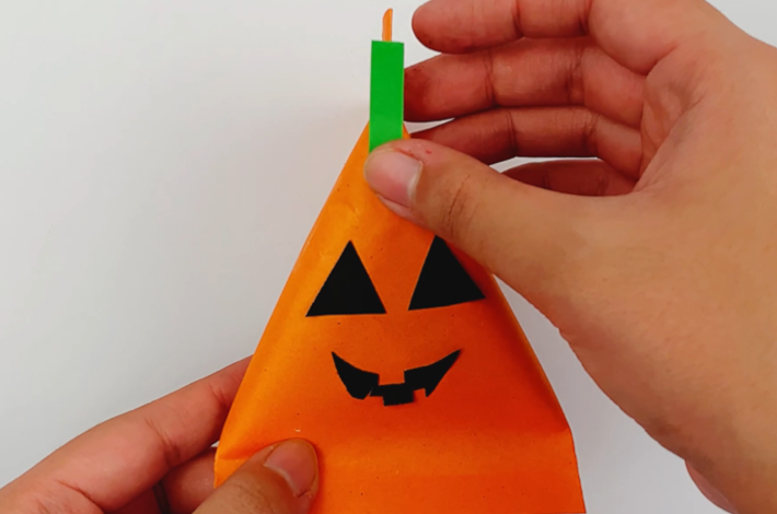 Two hands applying a small strip of green paper on the front as a stalk.