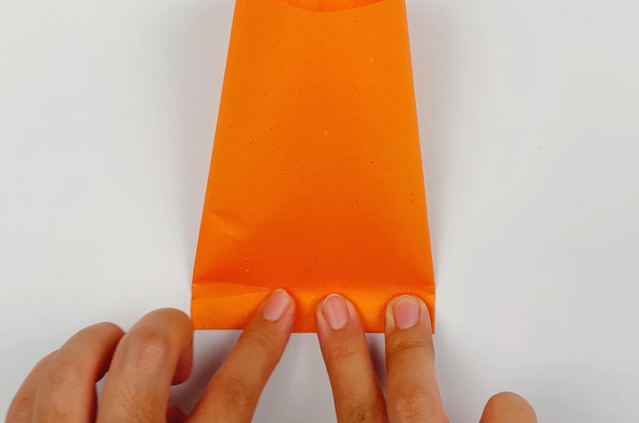 Two hands pushing down the bottom of the cylinder to stick the top and bottom half together.