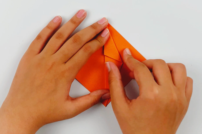 Two hands folding the top section over towards the center line. 