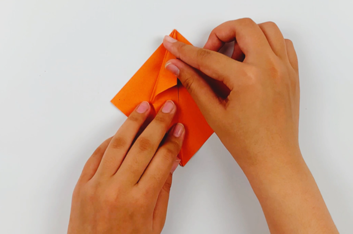 Two hands folding the top section on the left over towards the center line. 