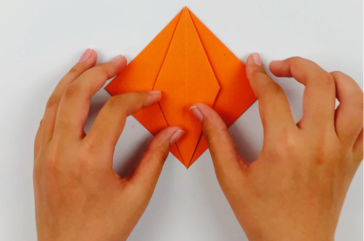 Two hands showing the folds forming a smaller diamond shape within the bigger diamond shape. 