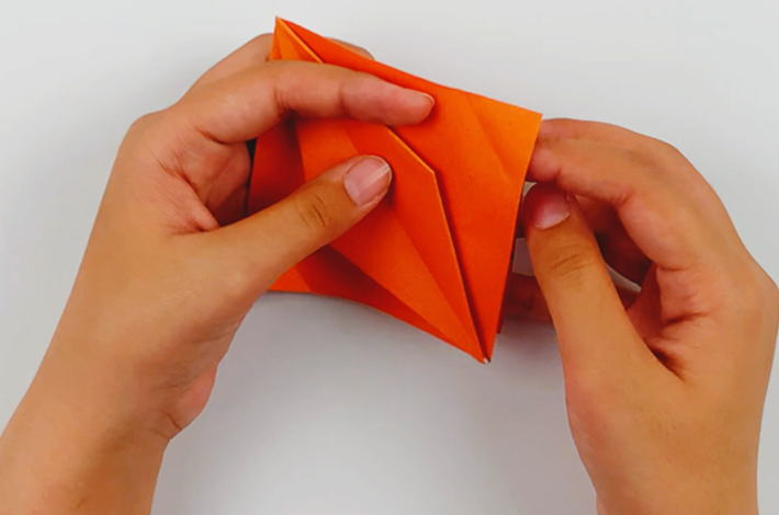 Two hands unfolding the left and right corners.