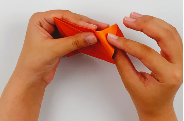 Two hands tucking the corners inside the folds made.