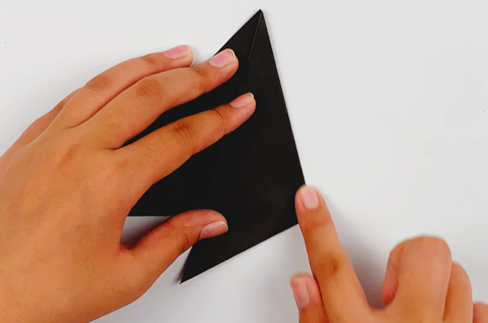Two hands folding the right-hand side of the triangle over to the center line. 