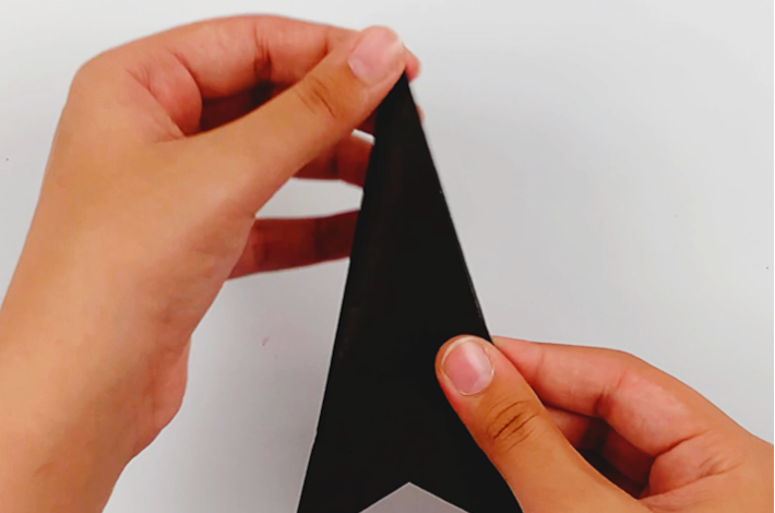 Two hands folding the right-hand side of the triangle over to the center line. 