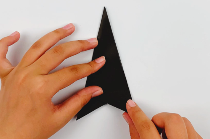 Two hands unfolding the bottom section of the paper. 