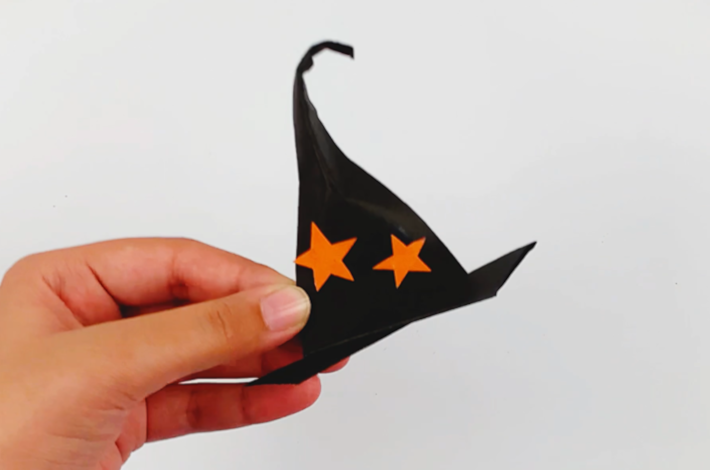 A hand holding a finished witch hat. 