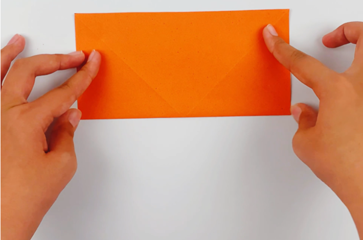 Two hands folding the paper in half.