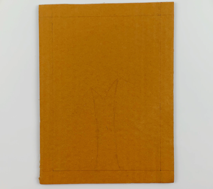 A piece of cardboard with lines drawn an inch inside the ends on all sides and a tree stump form in the middle.
