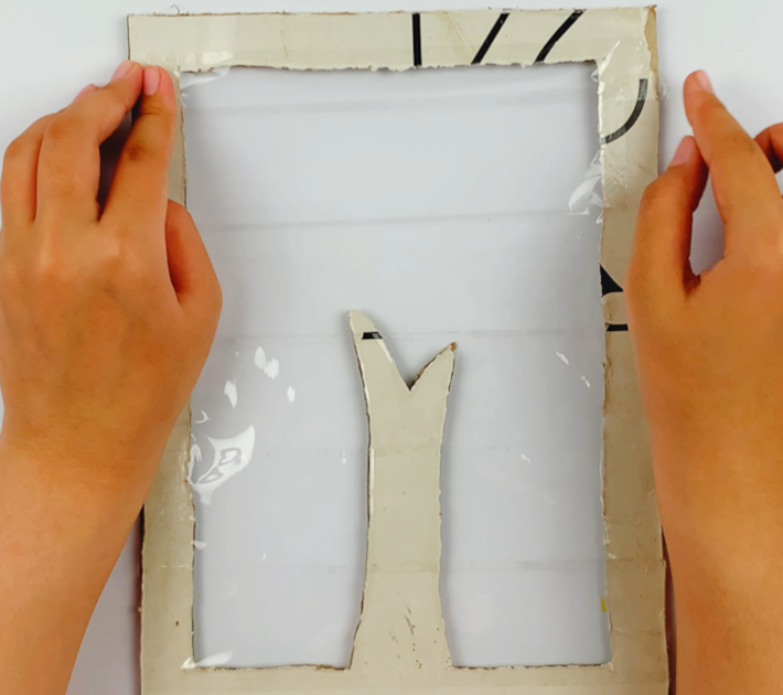 Two hands sticking Scotch tape all the way to the top of the frame. 