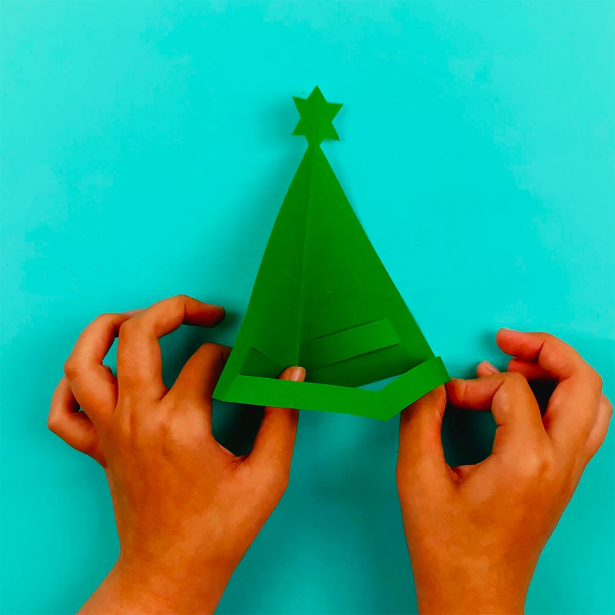 Two hands manipulating the bottom cut section of paper to make it stand out with a 3d effect.