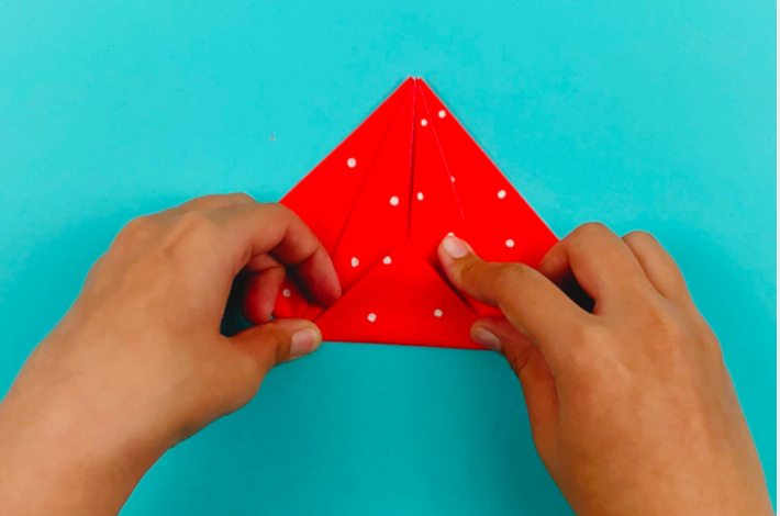 Two hands folding the bottom triangle upwards.