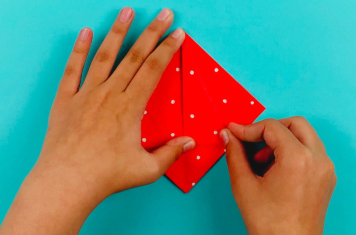 Two hands turning the paper over 180 degrees.