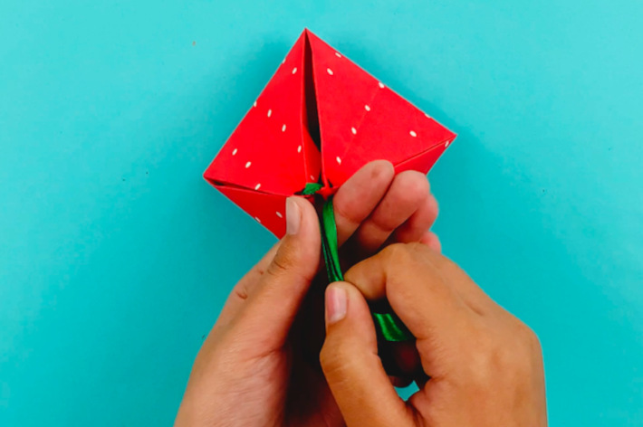 Two hands pulling the ribbon to secure the box.